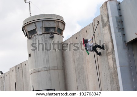 BETHLEHEM, PALESTINIAN TERRITORIES - MARCH 30: A Palestinian scales the Israeli separation wall during clashes at the Bethlehem checkpoint during Land Day protests on March 30, 2012.