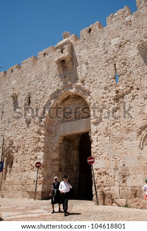 JERUSALEM - JUNE 2: An ultra-orthodox Jewish couple walks past Zion Gate in the southern wall of Jerusalem\'s Old City, June 2, 2012. The gate is scarred by bullet marks from the Six Day War in 1967.