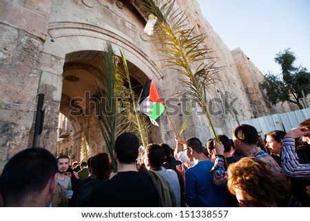 JERUSALEM - MARCH 24: A Palestinian flag waves among palm branches held by Christian pilgrims entering the Lions\' Gate of the Old City of Jerusalem in the annual Palm Sunday procession, March 24, 2013