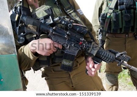 AL MA\'SARA, PALESTINIAN TERRITORY - JANUARY 18: An Israeli soldier rests a finger on the trigger of his gun during a protest against the Israeli separation barrier, Al Ma\'sara, West Bank, Jan 18, 2013