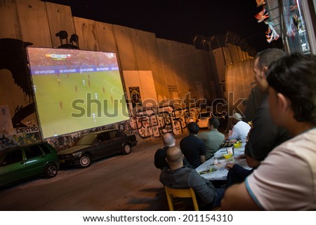 BETHLEHEM, WEST BANK - JUNE 18: Palestinians at a cafe watch a World Cup soccer game projected on the Israeli separation wall inside the West Bank town of Bethlehem, June 18, 2014.