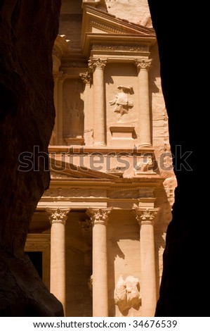 The Treasury seen through the Siq, a narrow canyon path through high rock cliffs, at Petra.