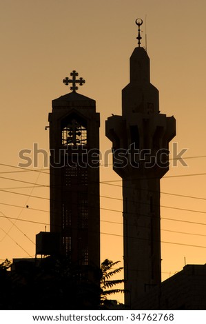 A minaret of the King Hussein Mosque and the steeple of the Coptic Orthodox Church silhouetted on the Amman skyline.