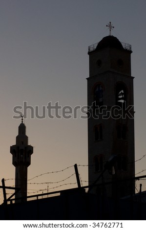 A minaret of the King Hussein Mosque and the steeple of the Greek Orthodox Church silhouetted on the Amman skyline.