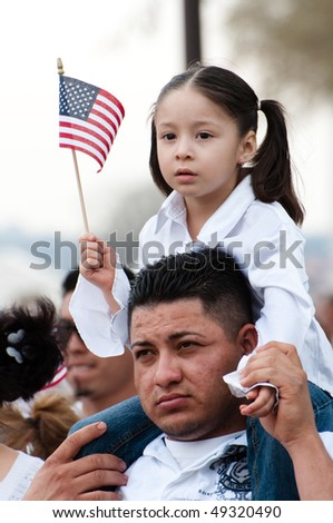 WASHINGTON, DC - MARCH 21: A girl and her father stand with some 200,000 immigrants\' rights activists flood the National Mall to demand comprehensive immigration reform on March 21, 2010 in Washington DC.