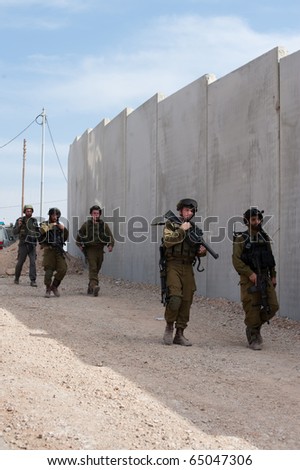 AL-WALAJA - NOVEMBER 13: Israeli soldiers stand in front of the Israeli separation barrier which threatens to encircle Al-Walaja on Nov. 13, 2010.