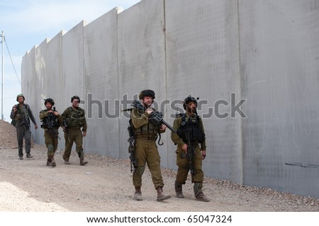 AL-WALAJA - NOVEMBER 13: On Nov. 13, 2010, Israeli soldiers stand in front of the Israeli separation barrier which threatens to encircle Al-Walaja.