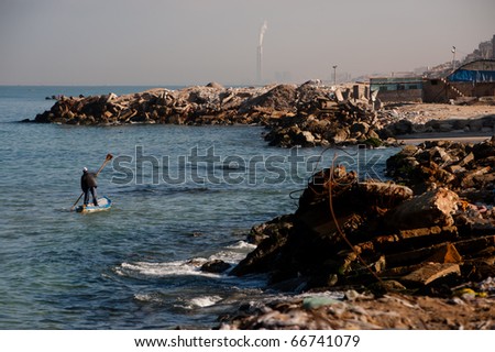 GAZA CITY - NOVEMBER 7:  A Gaza fisherman paddles his boat along the rubble-strewn Mediterranean shore on Nov. 7, 2010. Gaza\'s once large fishing fleet has been crippled by the Israeli blockade. .