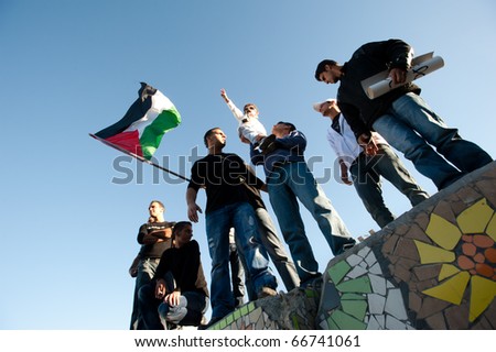 EAST JERUSALEM - DECEMBER 3: A boy makes a peace sign as protesters fly the Palestinian flag at a rally against house demolitions by Israeli authorities in the Al-Issawiya neighborhood on Dec 3, 2010 in EAST JERUSALEM.