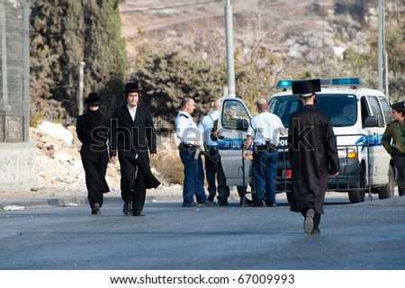 JERUSALEM - DECEMBER 3: Orthodox Jews pass Israeli police standing guard on Dec. 3, 2010, in the neighborhood of Sheikh Jarrah, historically an Arab Palestinian neighborhood in East Jerusalem.