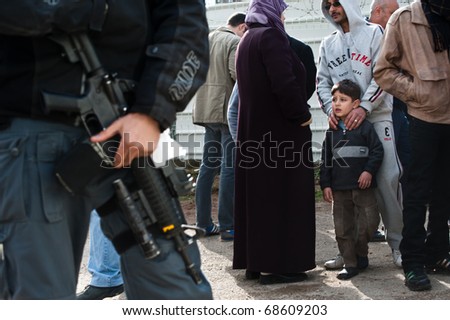 EAST JERUSALEM - JANUARY 9: A Palestinian child watches Israeli security agents guarding a building demolition in Sheikh Jarrah to make way for new Jewish settlements in East Jerusalem on Jan 9, 2011 in East Jerusalem.