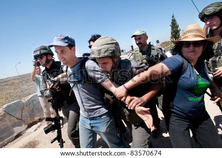 AL-WALAJA, OCCUPIED PALESTINIAN TERRITORIES - AUGUST 27: Israeli Border Police arrest an Israeli activist protesting the separation barrier encircling Al-Walaja, West Bank, Occupied Palestinian Territories on August 27, 2011.