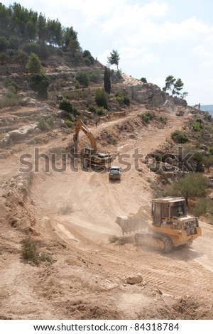 AL-WALAJA, OCCUPIED PALESTINIAN TERRITORIES - SEPTEMBER 5: Caterpillar construction equipment clears land for Israel\'s separation barrier surrounding the West Bank town of Al-Walaja on Sept 5, 2001.