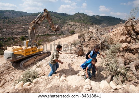 AL-WALAJA, OCCUPIED PALESTINIAN TERRITORIES - SEPTEMBER 5: Palestinian unidentified boys pass equipment near olive trees cut down to make way for Israel\'s separation barrier surrounding Al-Walaja, Sept 5, 2001.