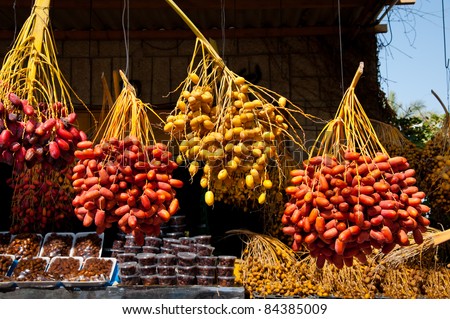 Fresh date fruits hang on stalks at a market in the West Bank Palestinian city of Jericho. Dried dates sit in packages on nearby shelves.