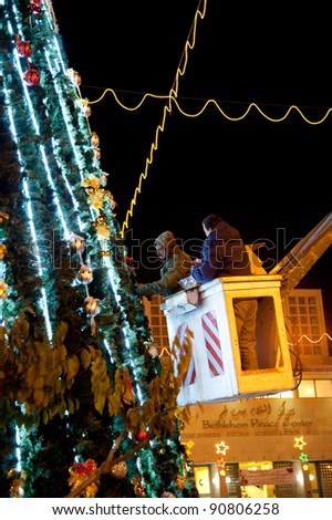 BETHLEHEM, OCCUPIED PALESTINIAN TERRITORIES - DECEMBER 11: Workers put finishing touches on the Christmas tree towering above Manger Square in the West Bank town of Bethlehem on Dec 11, 2011.