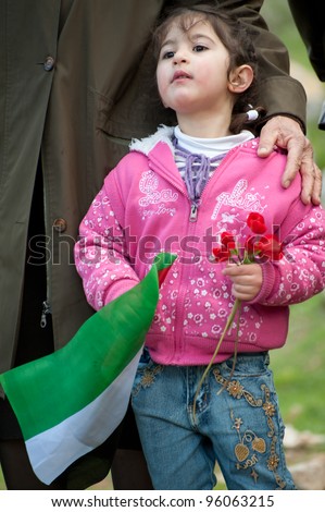 BEIT JALA, PALESTINIAN TERRITORIES - FEBRUARY 24: An unidentified Palestinian girl holds roses and the Palestinian flag during a protest against the Israeli separation barrier in Beit Jala, West Bank, Feb 24, 2012  in Occupied Palestinian Territories.