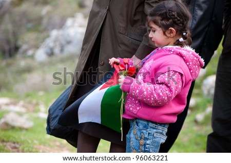 BEIT JALA, PALESTINIAN TERRITORIES - FEBRUARY 24: An unidentified Palestinian girl holds roses and the Palestinian flag during a protest against the Israeli separation barrier in Beit Jala, West Bank, Feb 24, 2012 in Occupied Palestinian Territories.