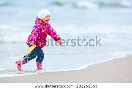 Cute girl is running on the beach (Late fall. Klaipeda, Lithuania).