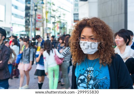 TOKYO CITY, JAPAN - 02 MAY 2013: Asian woman is wearing white protective mask in the crowd of people. Tokyo city, Japan