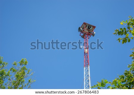 Speaker on high tower and clear blue sky with tree as a foreground