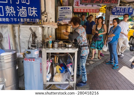 Taipei, Taiwan - May 3, 2015: Taiwanese female chef cooking local breakfast while people line up waiting for their queue.