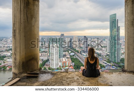 Young women meditates in yoga position on high building. Unique concept of meditation, spirituality and balance.