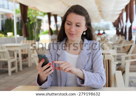 Girl using smart phone in a restaurant terrace with an unfocused background
