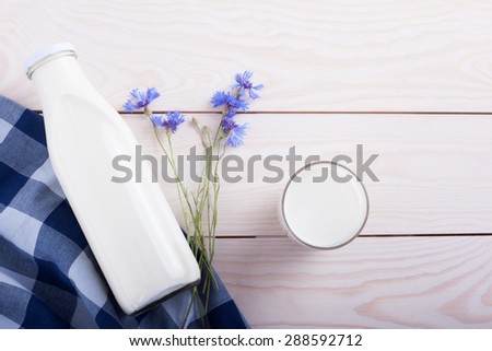 Milk cup and bottle on wooden table with flower