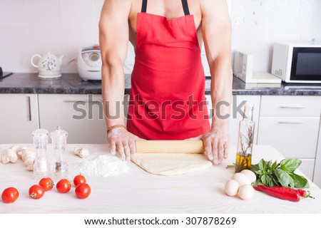 muscle man cooking pizza in the kitchen