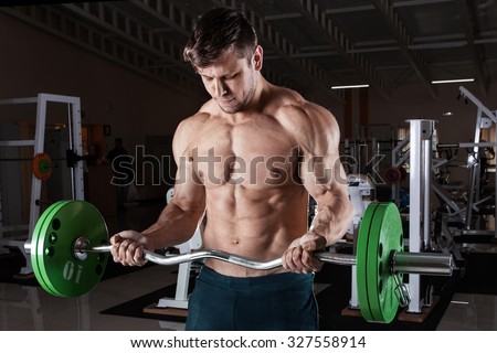 Man at the gym. Man makes exercises with barbell