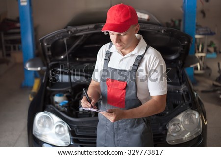 Car mechanic preparing checklist in workshop
