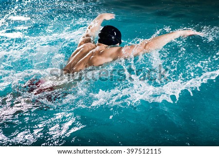 Young healthy man with muscular body swims in swimming pool