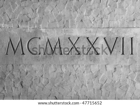 Roman numerals engraved in textured stone on outer wall of an historic Courthouse building in Santa Barbara, California.