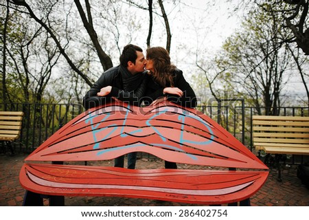 Young beautiful stylish couple kissing at the kiss bench