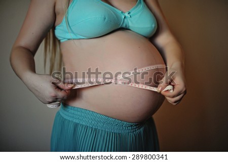 Pregnant woman holding meter tape on her baby bump