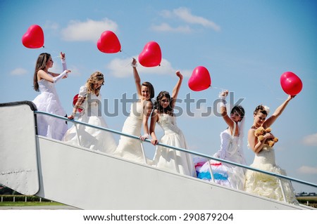 funny brides with balloons at the hand on the airport