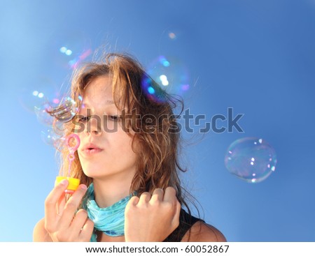 Girl on a beach inflates soap bubbles