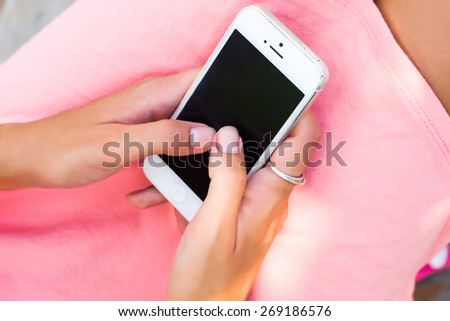 Young  woman writing massage,in glamour outfit.Woman in pink dress at the park, enjoying the summer day, cool accessories.Write massage,girl with phone,white smartphone,telephone calls,black screen