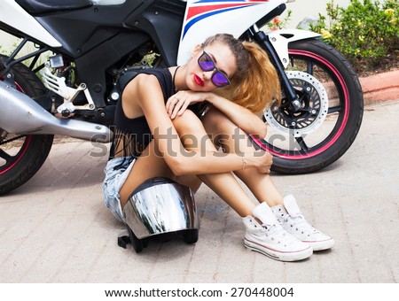 Young hipster girl having fun and going crazy, wearing glasses motorcycle clothes and bright make up. Show rock n roll and funky emotions.Lifestyle background.