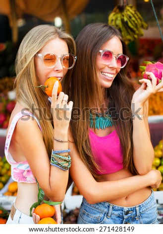 Beauty Model Girl takes oranges and fruits. Beautiful Joyful teen girl .Having fun on fruit market.white teeth and natural beauty.Summer mood street style,fashion look.young girls show funny emotions