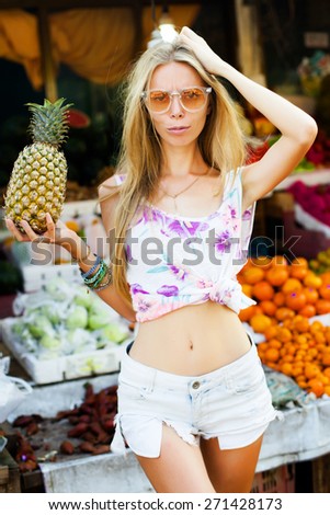 Beauty Model Girl takes Pineapple. Beautiful Joyful teen girl with freckles.Having fun on fruit market.natural beauty,funny emotions.Summer mood street style,fashion look.Going  crazy and having fun.