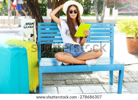 closeup portrait of happy woman in glasses using tablet pc in the airport wear summer clothes.Relaxing after long trip.beautiful young woman in heat sitting in park and holding tablet and smiling