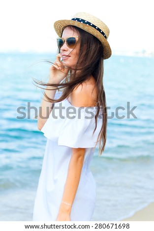 Young woman call to her friends and updating her social network status while relaxing at the beach.woman funky happy wearing sunglasses and beach hat having summer fun during travel holidays vacation.