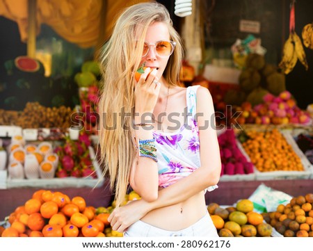 Beautiful Joyful teen girl eating orange on fruit market,enjoy hew summer weekends,showing funny faces,playing with fruits,summer mood.lovely woman\'s portrait.summer diet,detox,heathy lifestyle