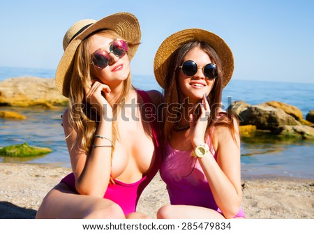 Attractive best friends having  fun on the beach,Laughing and having fun,Pretty smiling laughing tanned sexy sisters in summer have fun outdoor on the beach.bikini on sea background.Toned,glowing skin