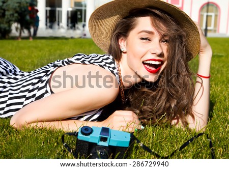 Outdoor lifestyle portrait of stylish girl laughing and smiling holding retro camera.Beautiful sexy woman,evening makeup wearing short dress,summer fall collection perfect in park sun shine,top skirt