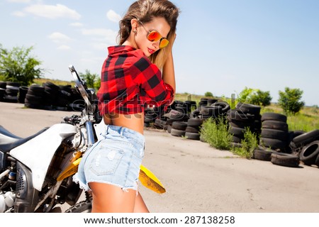 Young sexy woman,wear denim summer outfit and holding mirrored sunglasses,perfect glowing tan skin,attractive and,joy and happiness,trim,athletic figure,perfect female body,Motorcycles and drift show