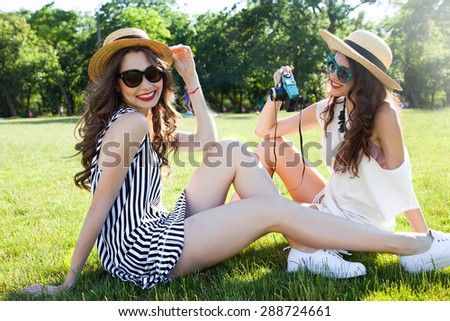 Fashion portrait of young teenagers having  fun on the ground and make self pictures together.Best friends laughing