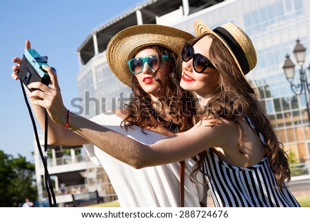Fashion portrait of young teenagers having  fun on the ground and make self pictures together.Best friends laughing